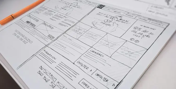 A hand-drawn wireframe of an application on a desk