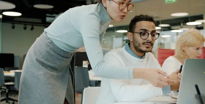 An IT specialist assisting a colleague at their workstation